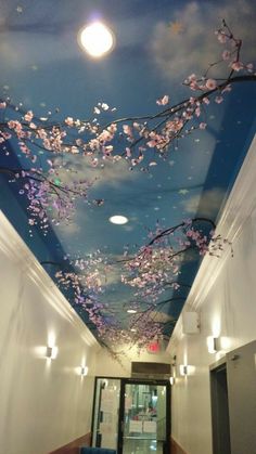 the ceiling is decorated with pink flowers and blue sky in an office building, which also has white walls