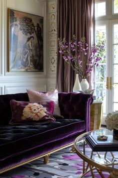 a living room filled with purple furniture and flowers in vases on the coffee table