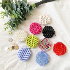 six different colored beads are on the table next to a plant and two pennies