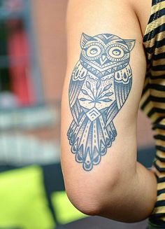 an owl tattoo on the back of a woman's arm