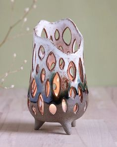 a ceramic candle holder sitting on top of a wooden table next to a twig