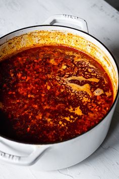 a pot filled with red sauce sitting on top of a counter