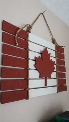 a canadian flag made out of wooden planks hanging on a wall with rope and string