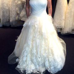 a woman in a white dress standing next to some dresses