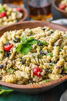 a wooden bowl filled with pasta salad and garnished with parsley on the side