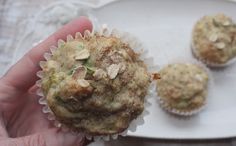 a hand holding a muffin on top of a white plate