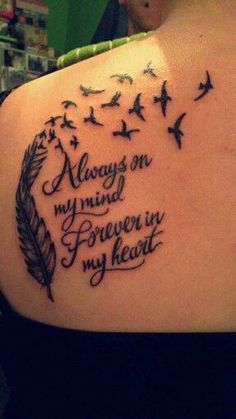 the back of a woman's shoulder with an ink quote on it and birds flying around