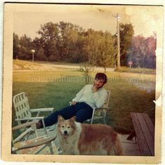 a woman sitting in a chair next to a dog on a lawn near a bench