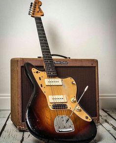 an electric guitar and amp sitting on top of a wooden floor in front of a white wall