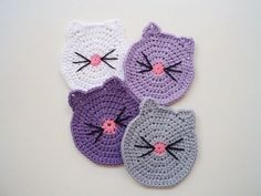 three crocheted cat coasters with pink, purple and white cats on them