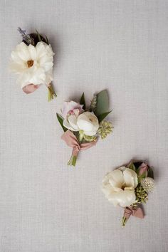 three white flowers are arranged on a gray surface