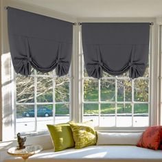 a living room filled with furniture and windows covered in gray draping next to a white couch