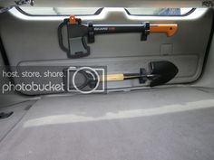 an orange and black shovel sitting in the back of a car with its door open