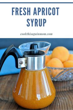 fresh apricot syrup in a glass carafe on a wooden table with oranges