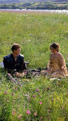 two people are sitting in the grass talking