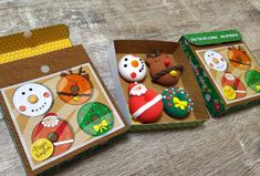 three boxes filled with decorated cookies on top of a wooden table