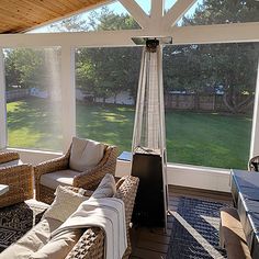 a screened porch with wicker furniture and an outdoor heater on the far side