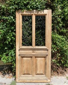 an old wooden door sitting in front of a bush