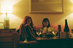 two women sitting on a couch with wine glasses in front of them and an empty bottle