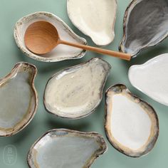 several different types of seashells on a green surface with a wooden spoon next to them