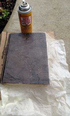 a can of spray paint sitting on top of a piece of paper next to a book