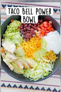 a bowl filled with chicken, lettuce, beans, and avocado