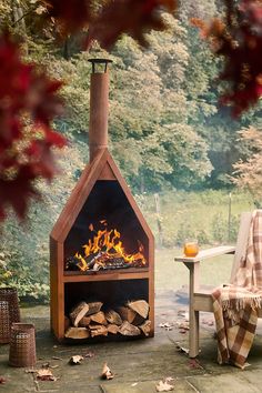 an outdoor fireplace with logs in the foreground and a chair on the other side