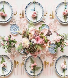 the table is set with plates and flowers on it, along with place settings for each plate