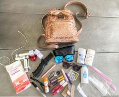 an assortment of personal care items laid out on the floor next to a handbag