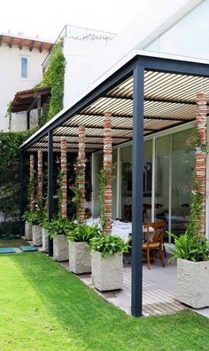 an outdoor patio with potted plants on the side and a dining area in the back