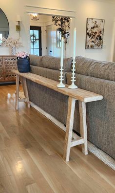 a wooden table sitting on top of a hard wood floor next to a gray couch