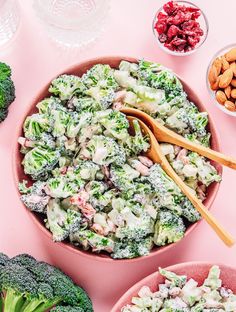 broccoli salad with almonds and cranberries in bowls on a pink surface