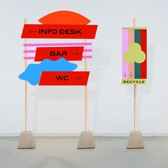 three wooden signs with different colors and shapes on top of each other in front of a white wall