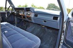 the interior of an older model truck with blue upholstered seats and dashboard controls