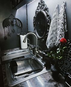 there is a sink in the kitchen with flowers on the counter and other items around it