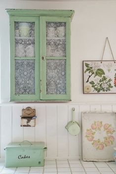 a green cabinet sitting next to a window in a room with white tile flooring