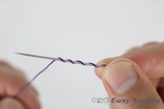 someone is knitting something with purple yarn on the end of a pair of scissors,