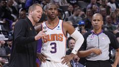 two basketball players standing next to each other in front of an arena full of people