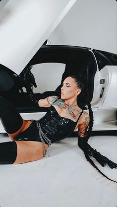 a woman sitting on the ground with her legs spread out and wearing black leather boots