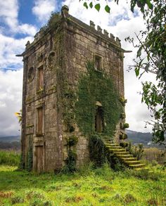 an old stone building with ivy growing on it's side and stairs leading up to the top