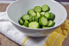 a white bowl filled with cucumbers on top of a yellow and white towel