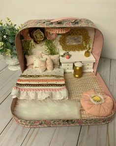 an open suitcase sitting on top of a wooden floor next to a potted plant