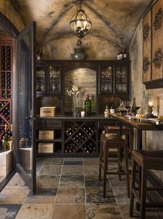 an image of a kitchen with wine bottles on the counter and chairs in front of it