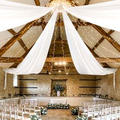 an indoor wedding venue with white draping and greenery