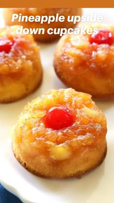 four pineapple upside down cakes on a white plate with cherries in the middle