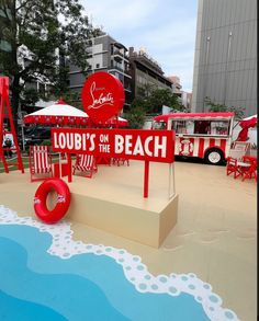 a sign that says loubi's on the beach next to some chairs and umbrellas