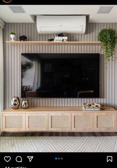 an entertainment center with a flat screen tv mounted on it's side and plants growing out of the top shelf