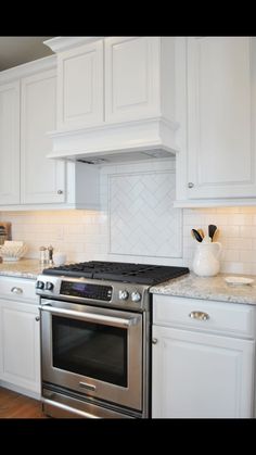 a stove top oven sitting inside of a kitchen next to white cabinets and counter tops