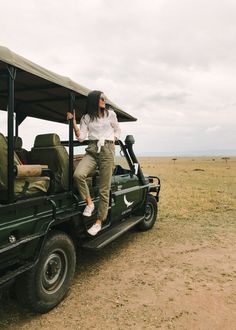 a woman sitting on the back of a green jeep