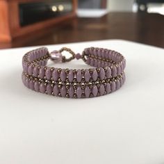 two purple beaded bracelets sitting on top of a table